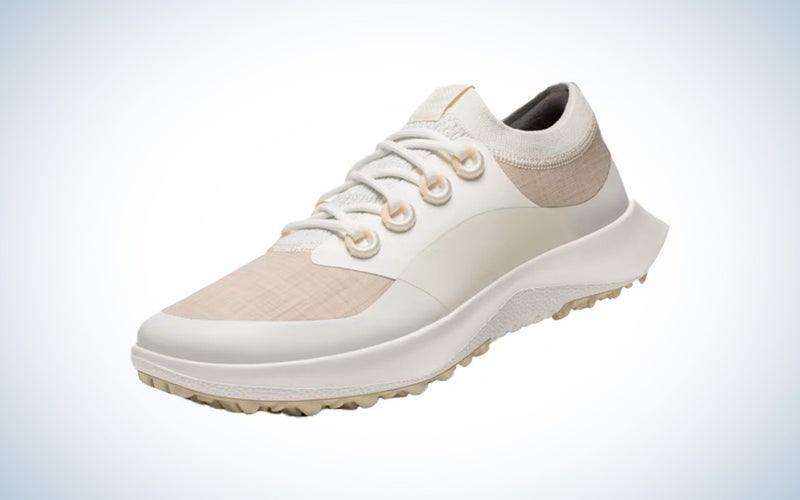 A pair of tan and white AllBirds golf shoes on a blue and white gradient background