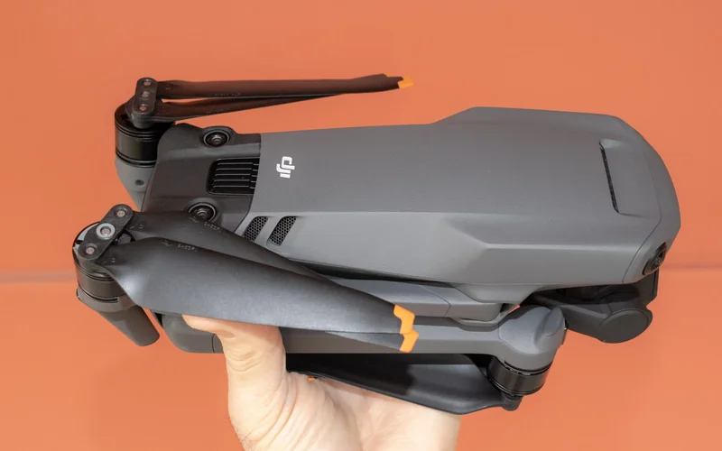 DJI Mavic 3 drone in a hand on an orange background